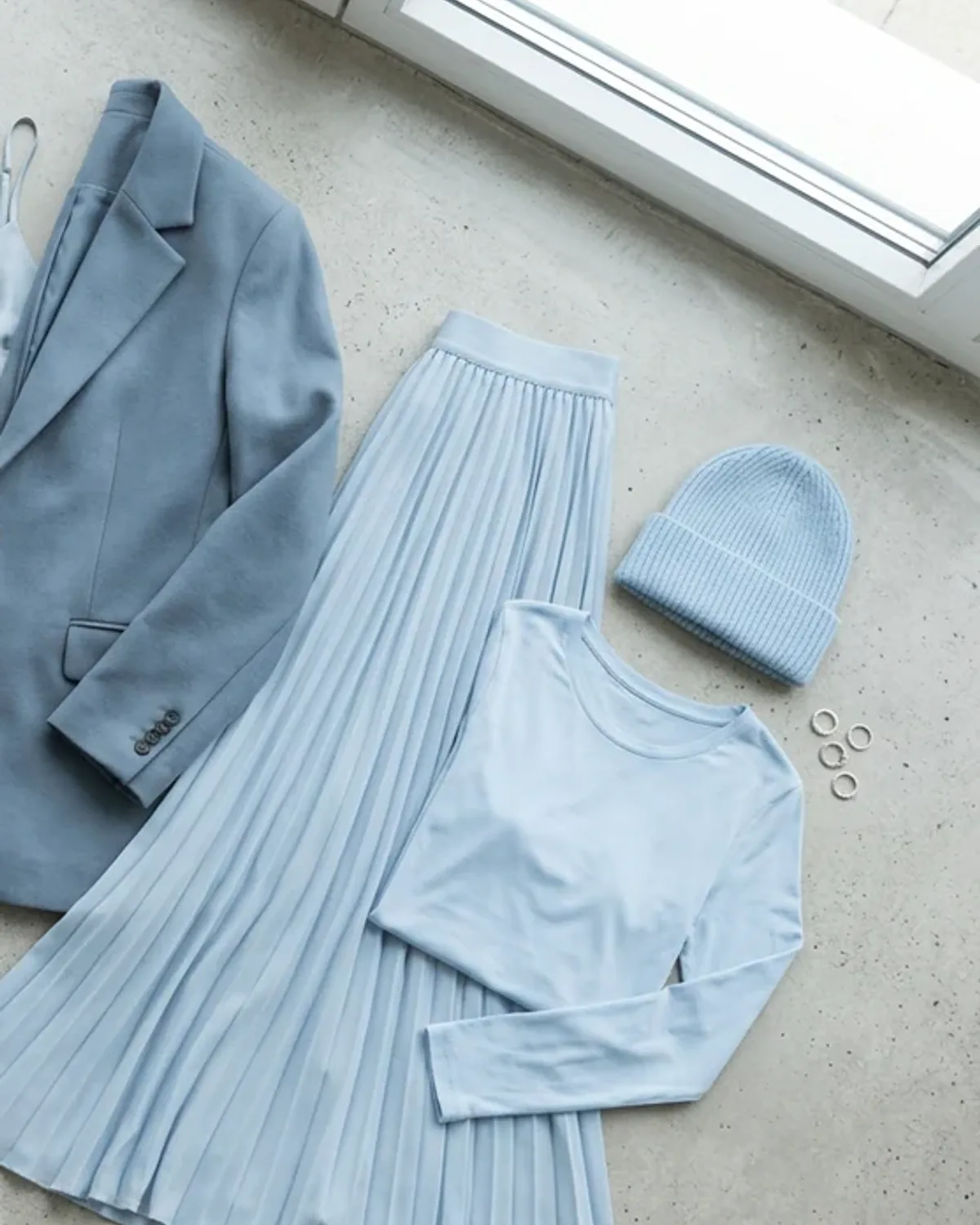 Light Summer weekend outfit flat lay: lavender sweatshirt, light-wash denim, soft white sneakers.